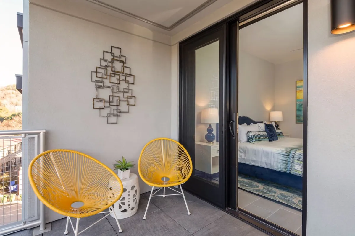 This image features a bright, welcoming entry space with yellow chairs, decorative wall art, and a sliding glass door that hints at seamless indoor-outdoor flow. The setup suggests an inviting transition area perfect for arriving home or preparing to step out into the city.