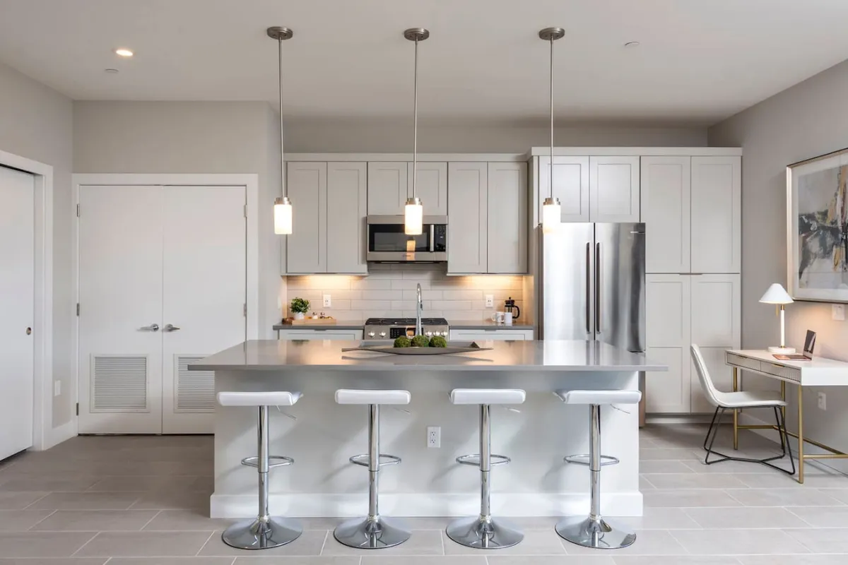 A kitchen with a sleek island countertop, bar stools, modern appliances, and prominent artwork, blending functionality with social appeal. The composition invites gathering for a quick bite, planning a food tour, or sharing stories from local brewery visits.
